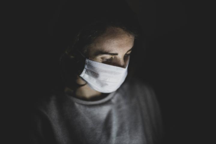 dark portrait of young woman wearing a mask